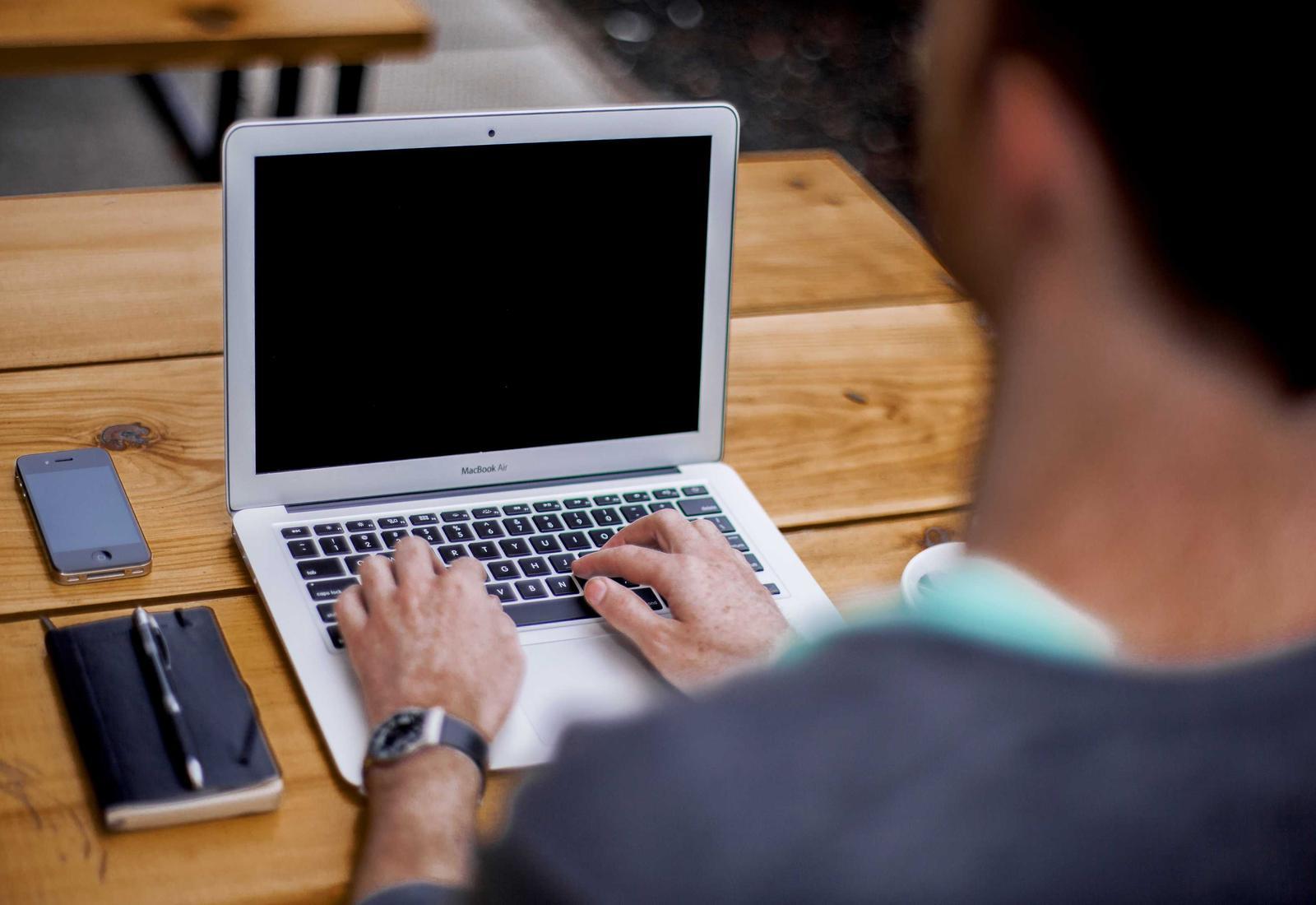 Hands typing on a laptop at a desk