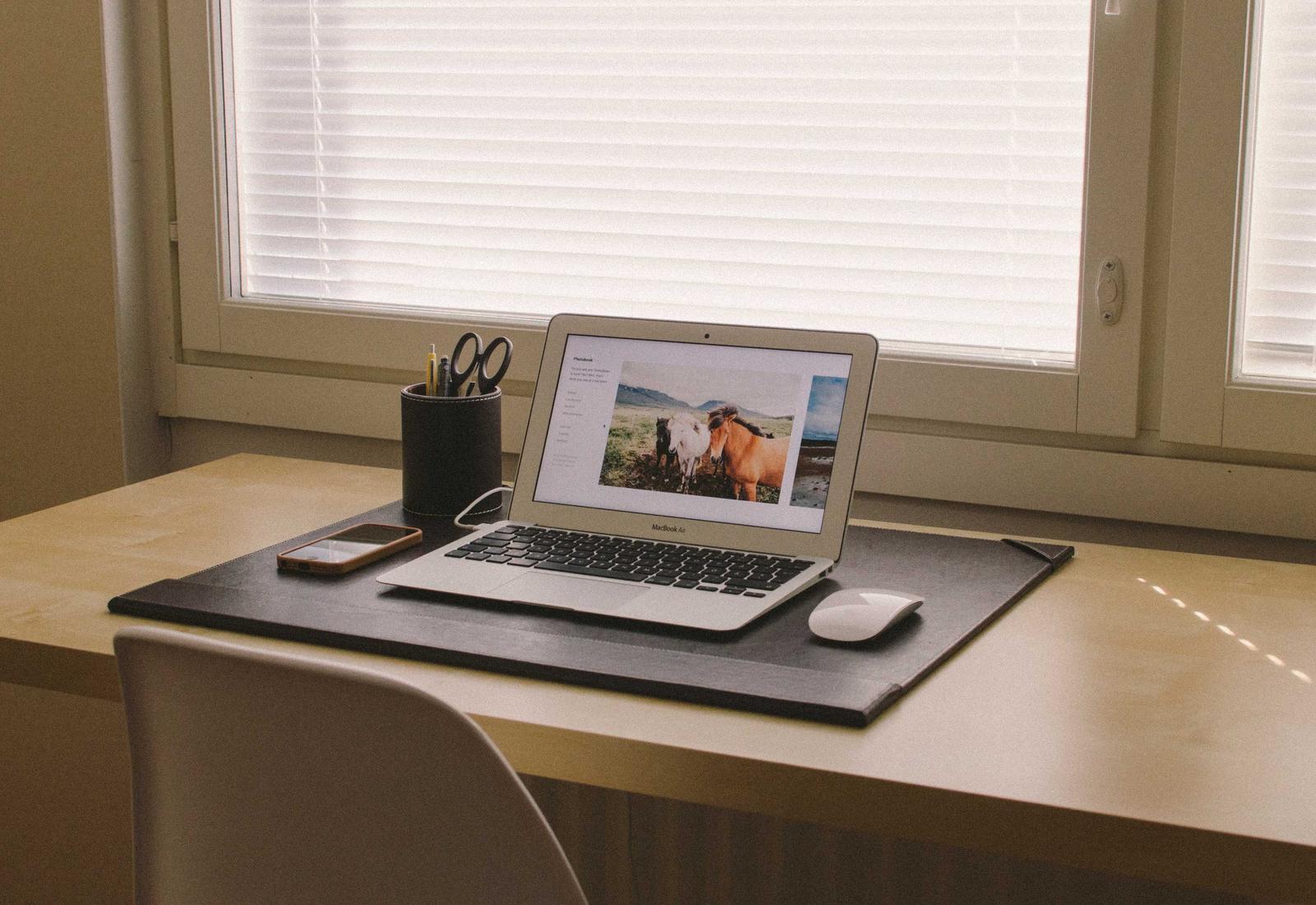 A laptop on a desk by an office window